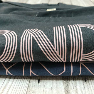 Pink geometric aurora font on denim blue tee