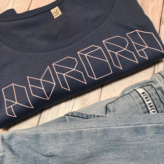Pink geometric aurora font on denim blue tee